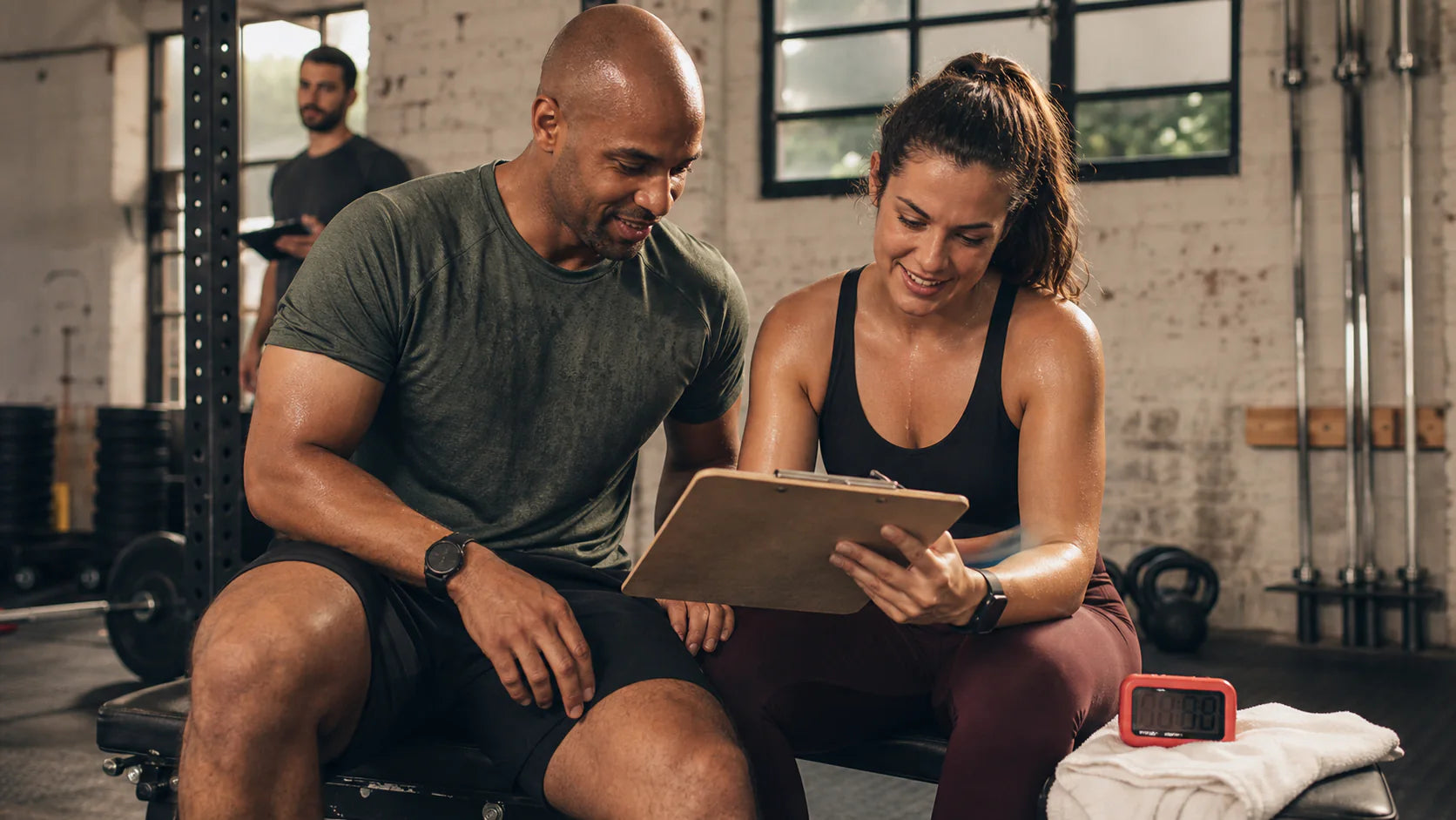 Two adult training partners reviewing a shared workout plan after a gym session